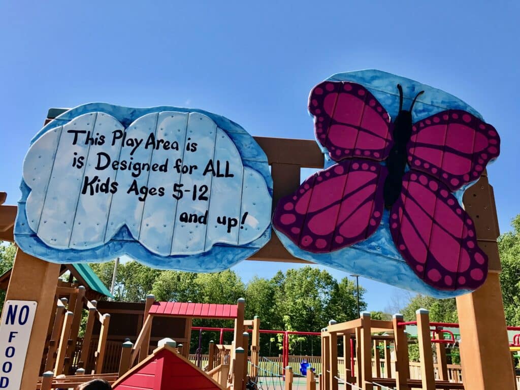 Sign with a bright pink butterfly at a Milwaukee-area Kayla's Playground in Franklin, marking the play area for kids ages 5–12 and up.