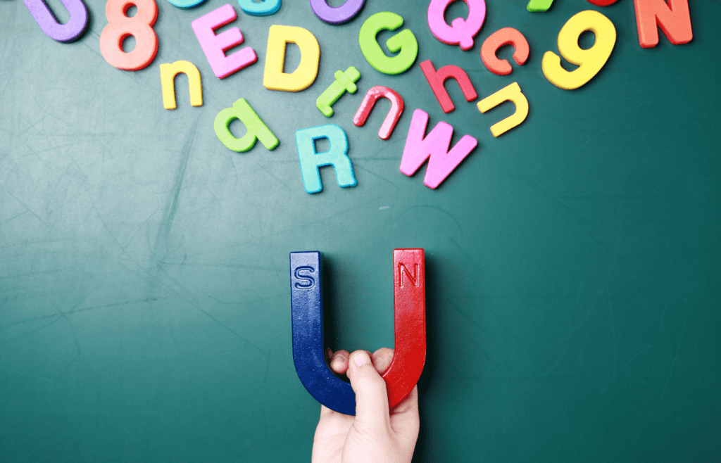 A large magnet pulls smaller magnets in the shape of letters towards it.