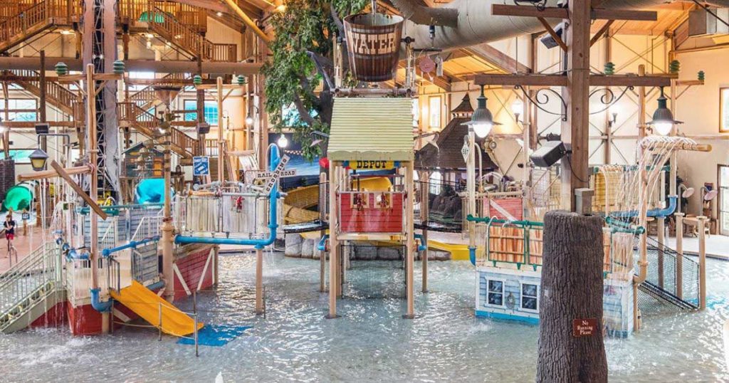 Multi-level water playground with slides, climbing nets, and water sprayers inside an indoor water park at the Ingleside Hotel in Pewaukee Wisconsin.