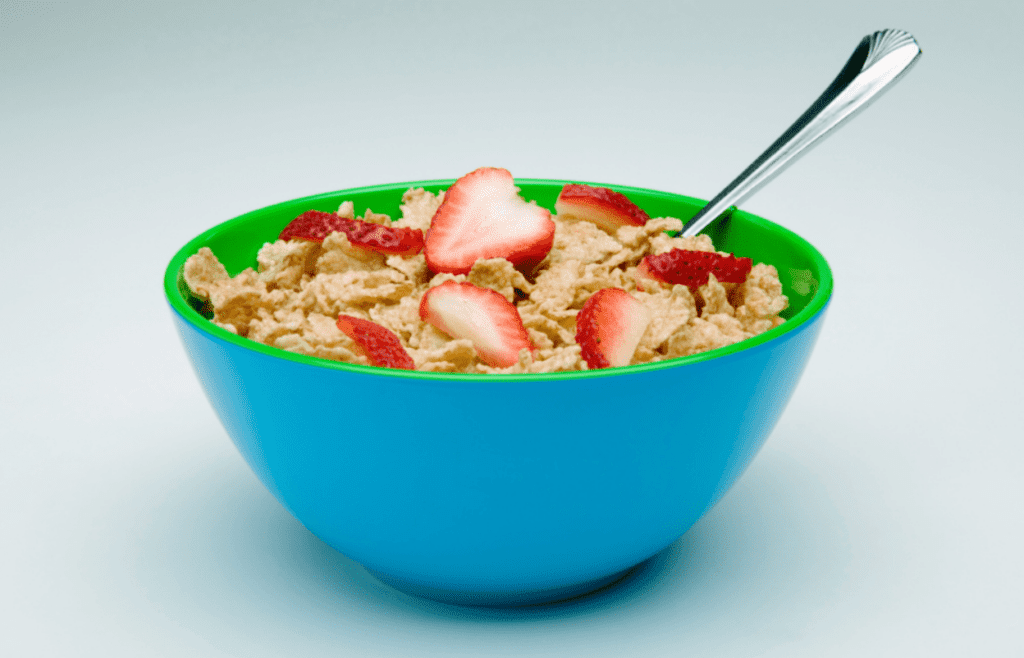 Bowl of cereal with sliced strawberries.