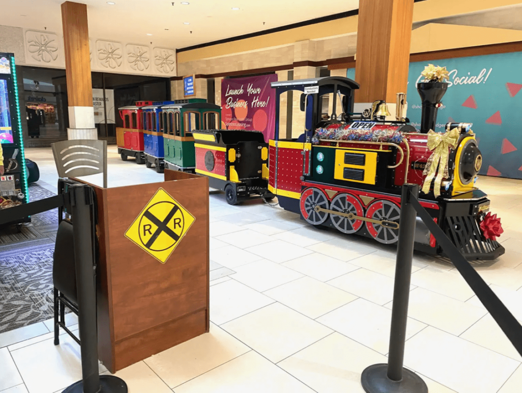 Colorful indoor trackless train ride set up at Southridge Mall, decorated with bows and festive lights.