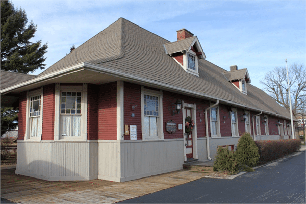 Historic red and cream train depot building in Cudahy, Wisconsin, with holiday wreath on door.