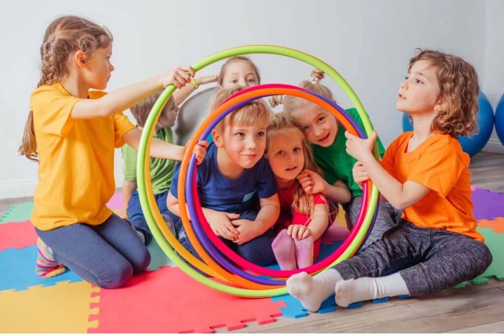Kids playing with hula hoops to represent the party idea little athlete's birthday bash for 3 year olds.