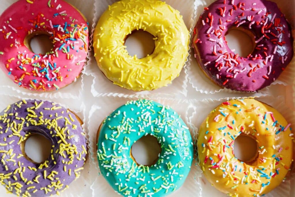 Half a dozen donuts with sprinkles on top to represent a donut party for young children.