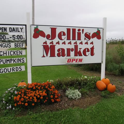 Entrance sign for Jelli’s Market in Helenville, Wisconsin, surrounded by pumpkins and flowers.