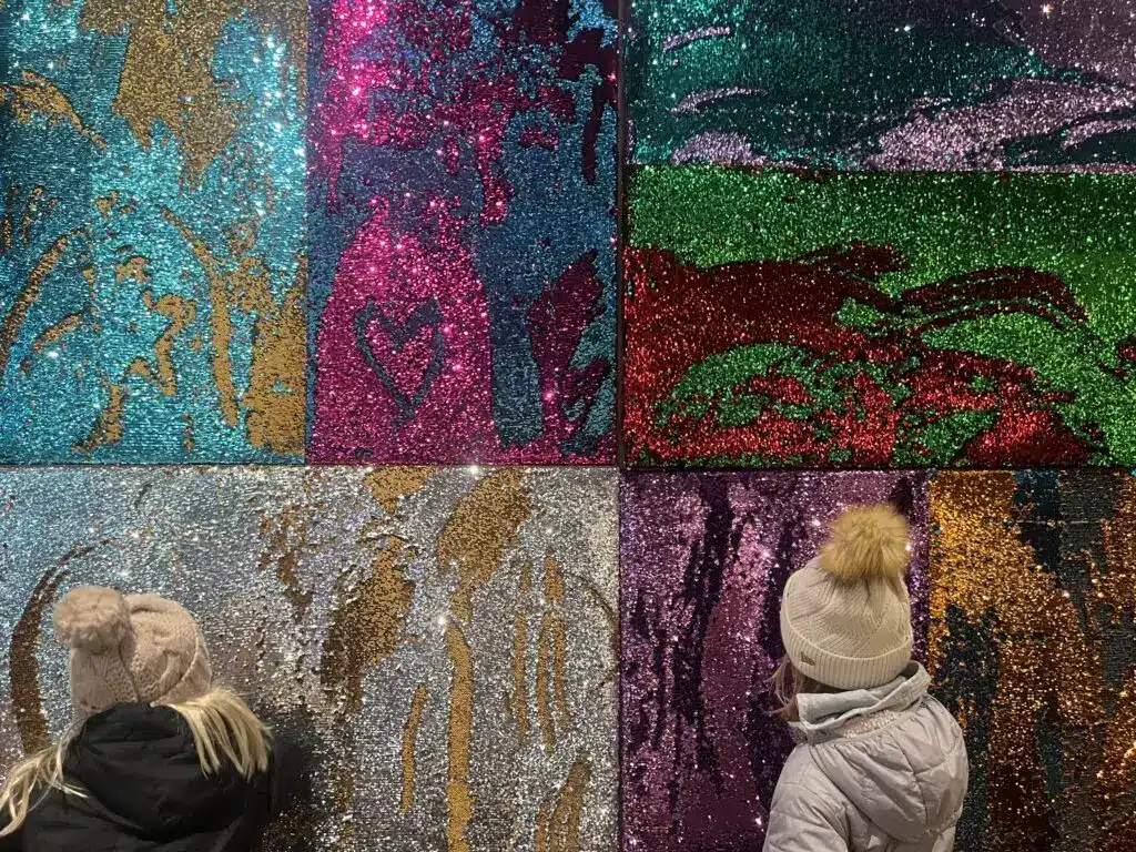Kids interacting with the colorful glitter wall at 3rd Street Market Hall.