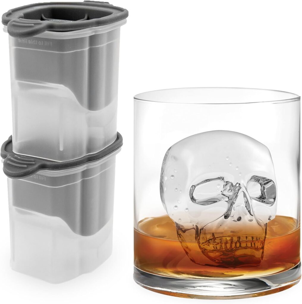 Two stacked ice molds and a glass with a skull-shaped ice cube and juice