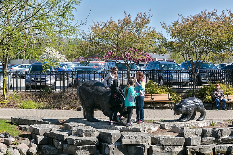 A family plays near the Life Lesson bronze sculpture of three bears on the riverwalk in Waukesha.