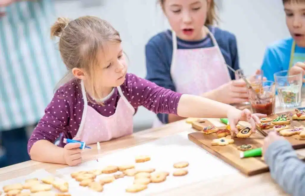 Children decorating sugar cookies with icing at a birthday party