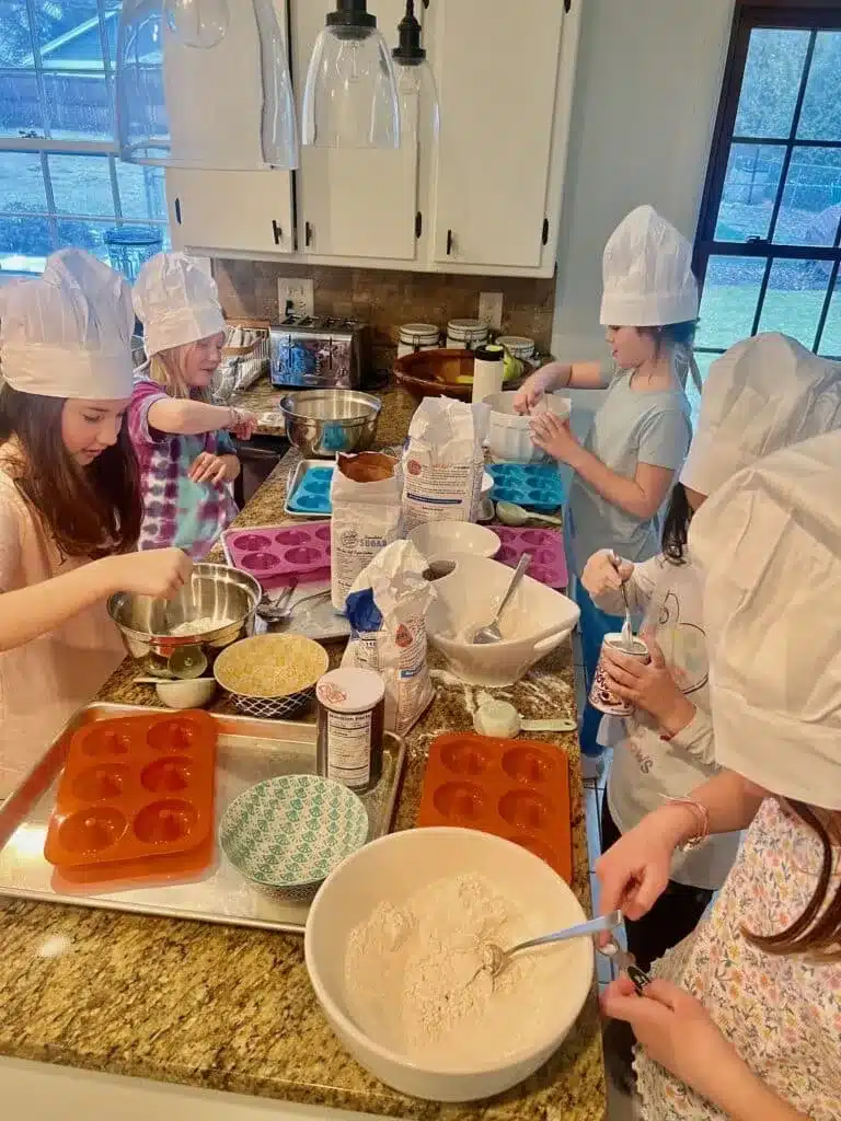 Kids wearing chef hats making donuts together in a kitchen