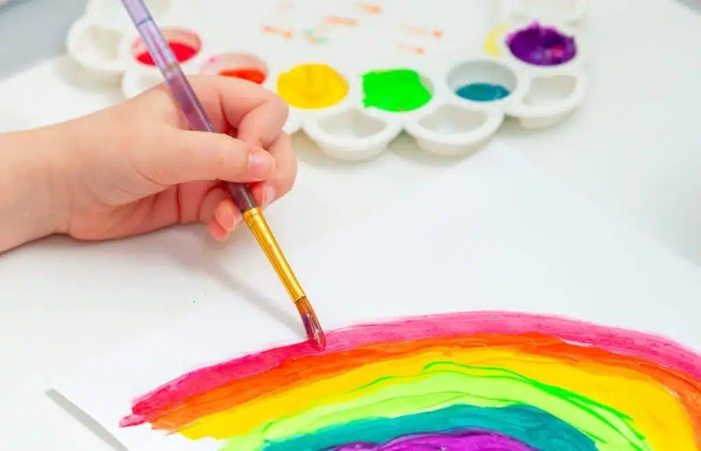 Child painting a rainbow during a paint and sip birthday party