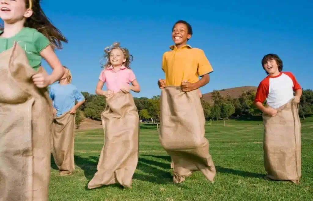 Kids laughing while racing in burlap potato sacks outdoors