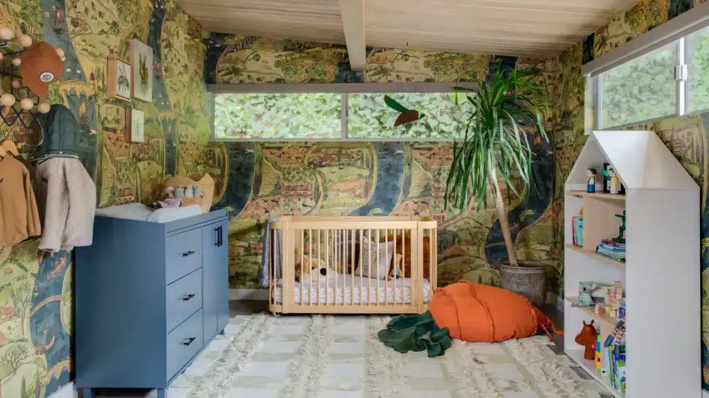Modern boho baby boy nursery with terracotta accent wall, rattan furniture, canopy crib, and natural textures – warm earthy nursery design trend 2025