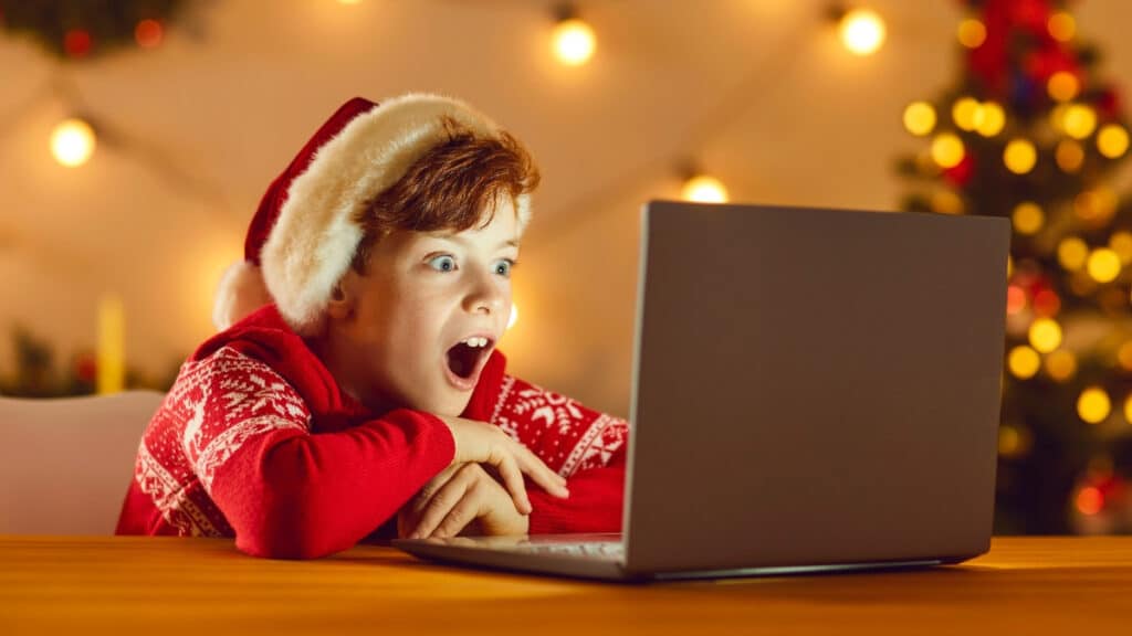 Boy watching a movie on a laptop - Christmas movie trivia for kids
