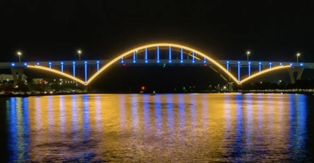 Hoan Bridge in downtown Milwaukee illuminated in blue and gold lights for Hanukkah, reflecting over Lake Michigan.