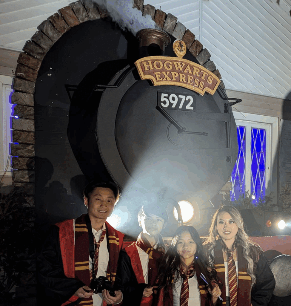 Students dressed in Harry Potter Themed costumes pose in front of the Hogwart's Express train display.