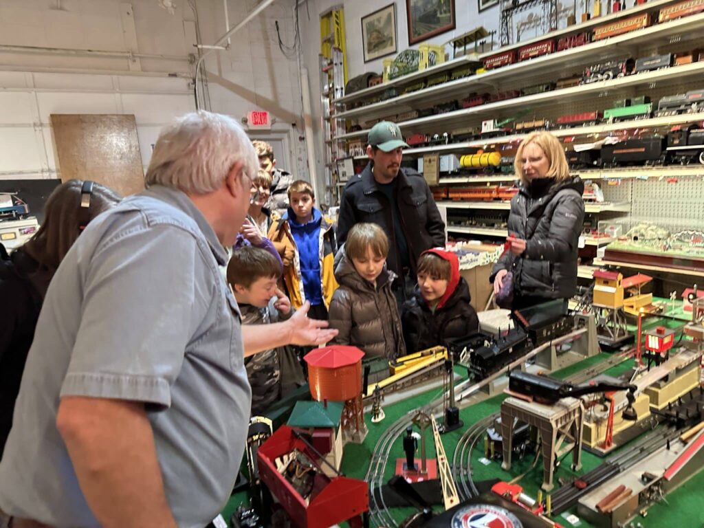 Children and adults gathered around a large model train display at the Milwaukee Lionel Railroad Club.