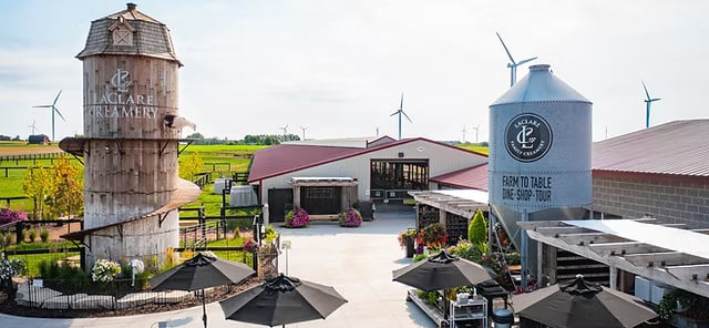 Aerial view of LaClare Creamery in Malone, WI with silo, goat walking on silo, and sign that reads "Farm to Table".