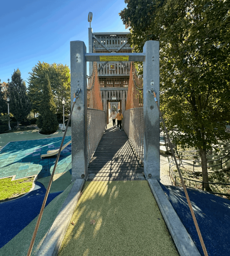 Children walking across a suspension bridge at Maggie Daley Park in downtown Chicago on a sunny fall day.