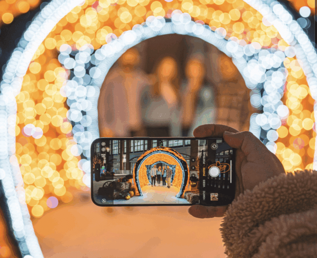 A hand holding a mobile phone with its camera on and taking a group photo