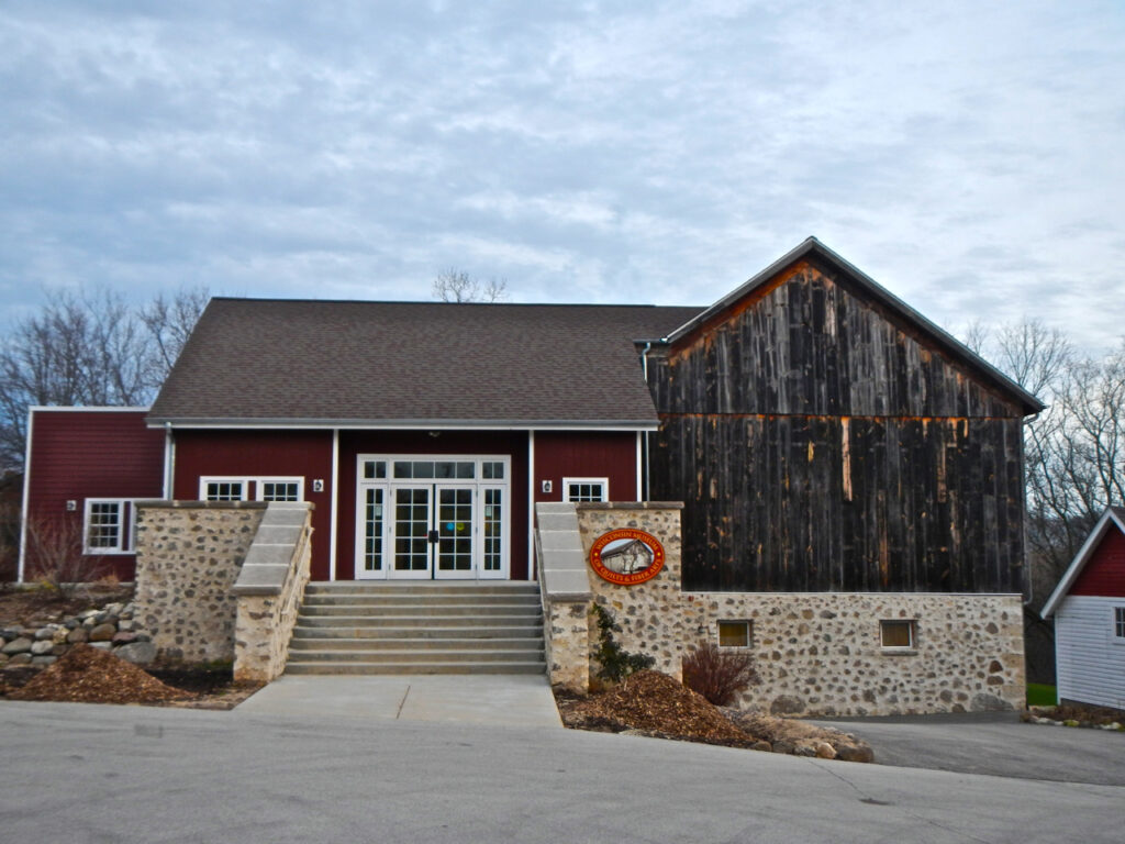 A rustic red barn-style building housing the Wisconsin Museum of Quilts and Fiber Arts.