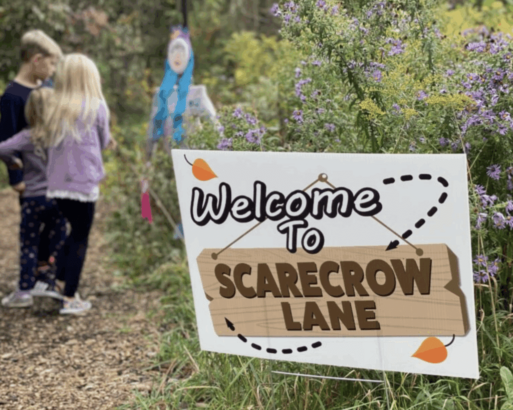 Kids going to the Scarecrow Lane path with a Welcome to Scarecrow Lane board