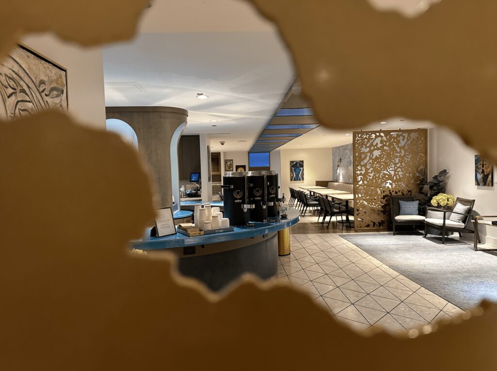 Lobby coffee station at The Gwen Chicago with modern blue counter, hot coffee dispensers, and gold decorative screen.