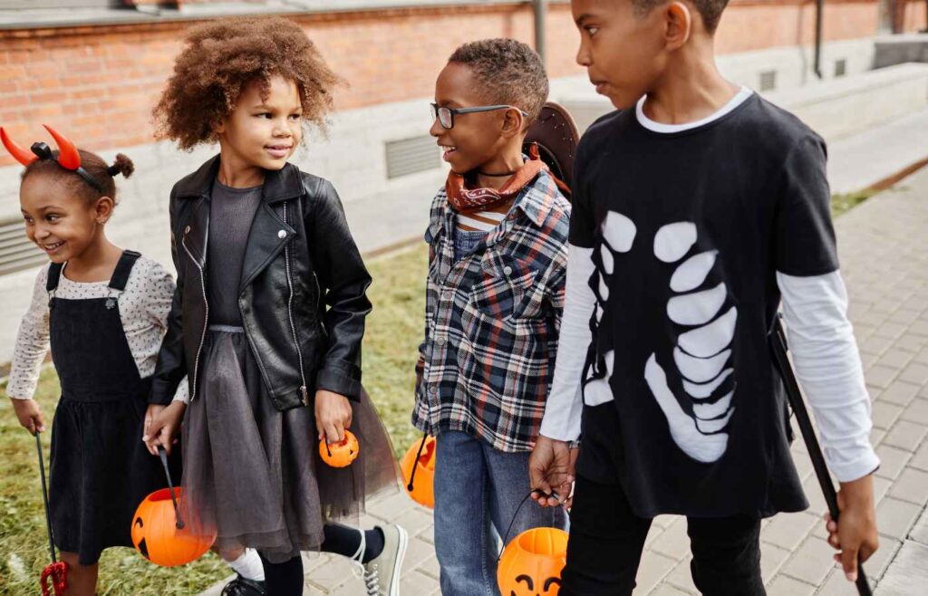 Four kids going on a Halloween trick or treat holding pumpkin baskets in Milwaukee