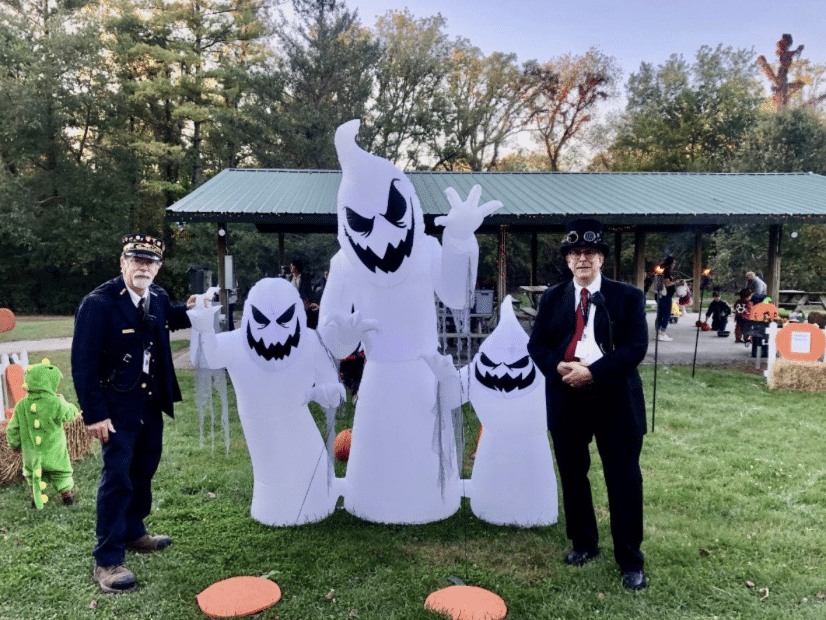 Two train conductor pose with ghost inflatables at the Trick or Treat Train event in East Troy.