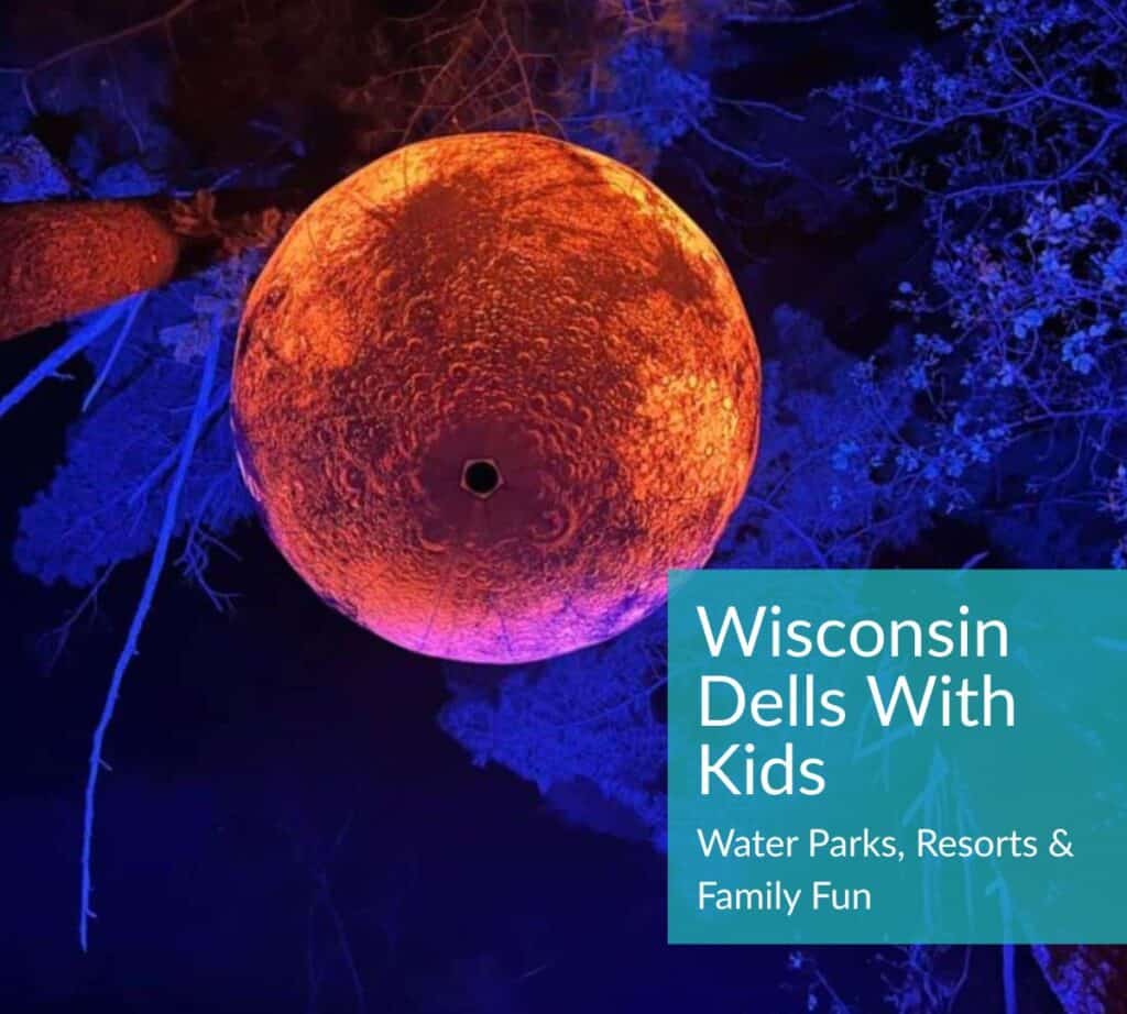 Illuminated orange moon installation against a blue-lit forest backdrop at Aquavia Lumina in Wisconsin Dells — featured image for “Wisconsin Dells With Kids: Water Parks, Resorts & Family Fun” blog post.
