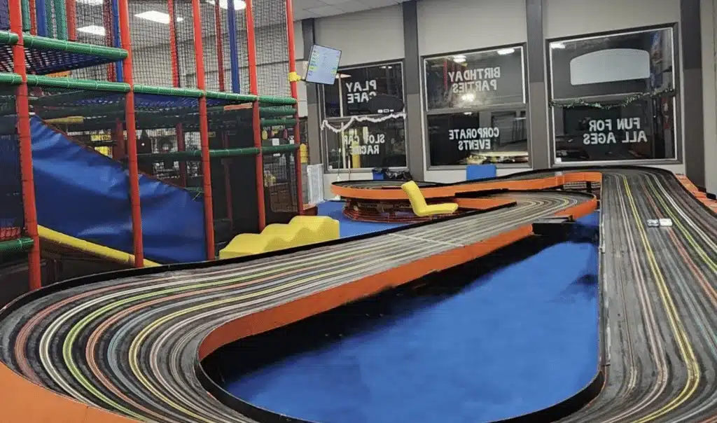 A slot car track with a view of a large play gym on its side at A Kid at Heart