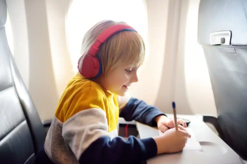 Five-year-old drawing on a travel doodle board in an airplane seat.