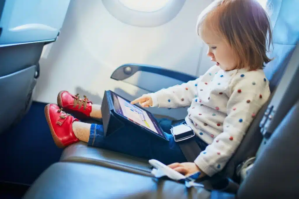 Toddler using a tablet on an airplane to play a travel app.