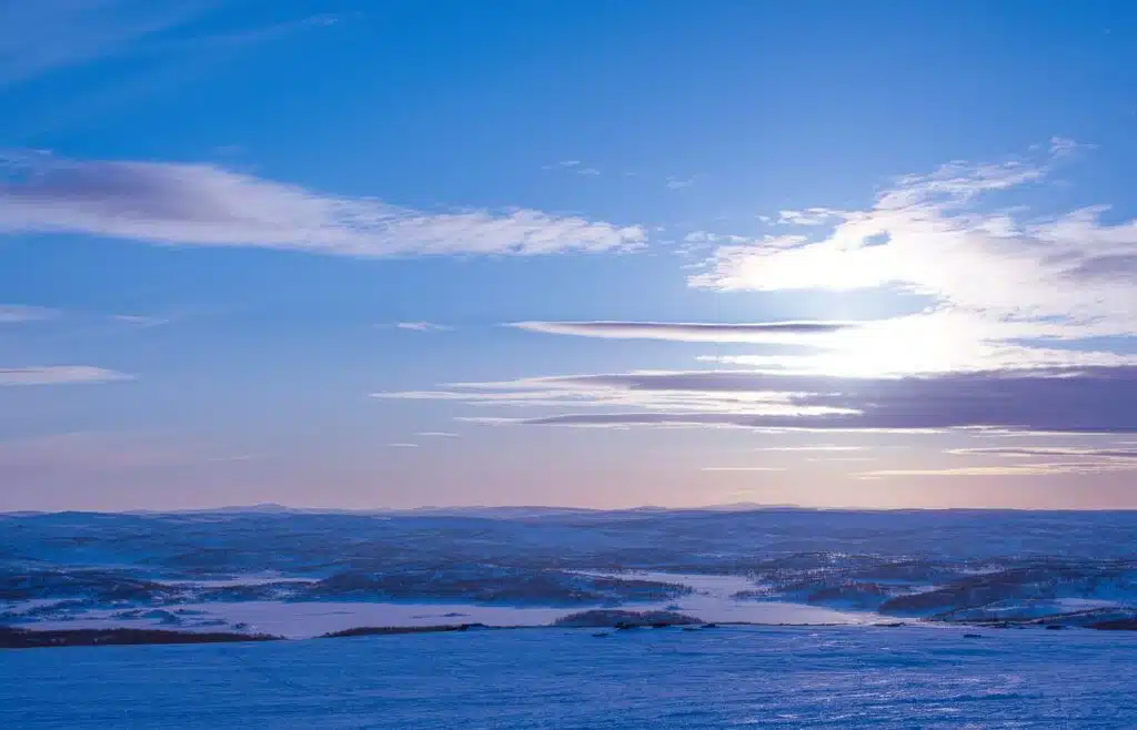 Snow-cored landcape with blue skies and thin clouds.