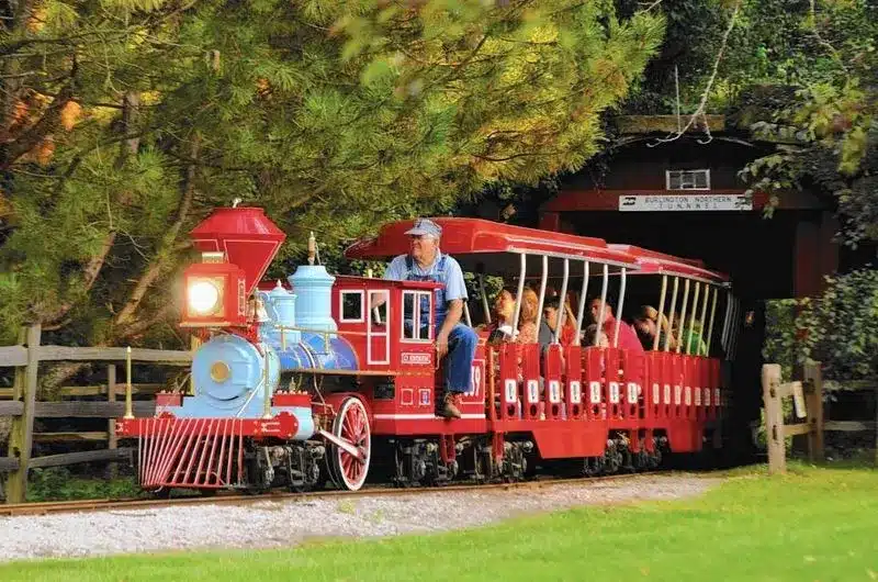Historic-style red train carrying families through Blackberry Farm in Aurora.