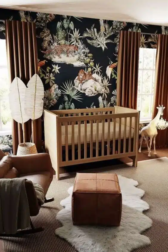 Baby nursery with bold jungle wallpaper, dark walls, and warm brown tones showing the moody accent wall trend for 2026.