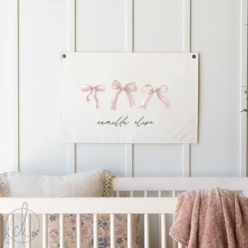 Neutral baby girl nursery with personalized bow name sign and soft blush textiles, representing the customization trend for 2026.