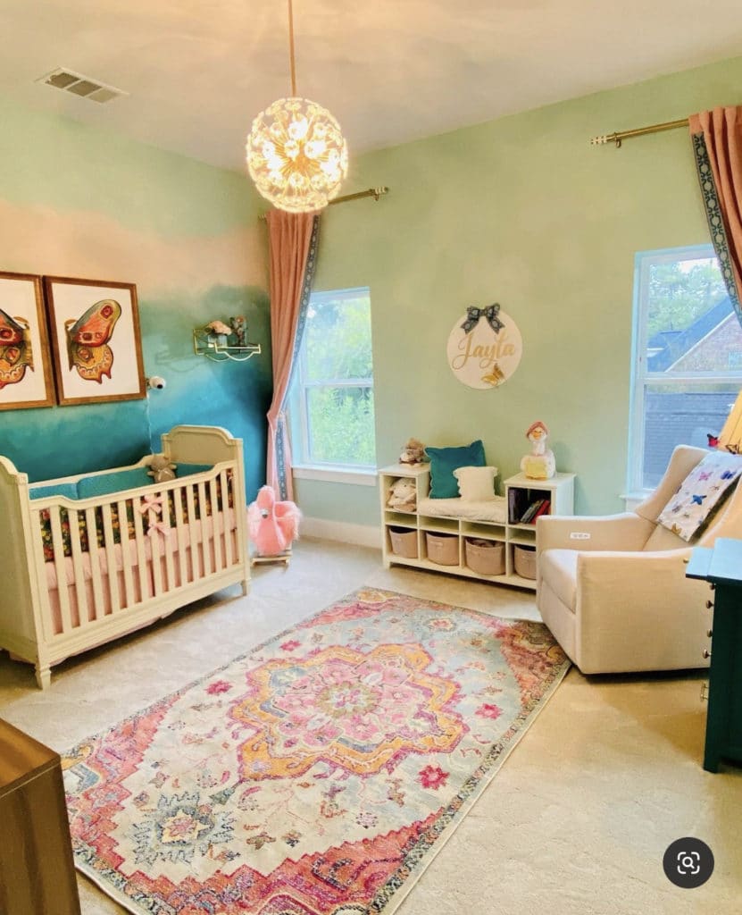 Baby girl nursery with soft green and blue walls, pink curtains, framed decor inspired by butterflies