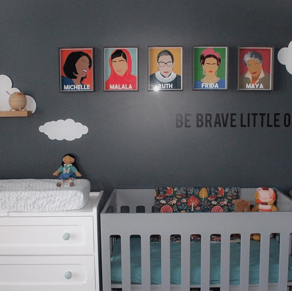 Baby girl nursery with gray walls, grey crib and wall portraits of famous women inspired by female icon theme design.