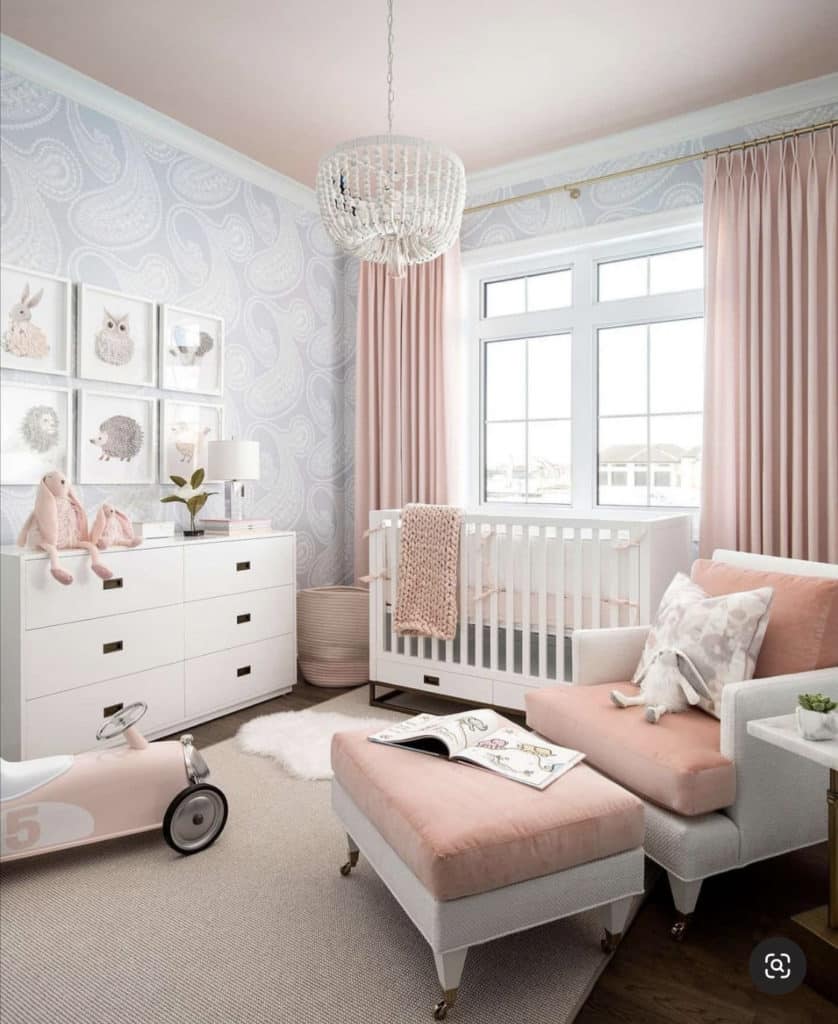 Baby girl nursery with soft pink cushions and curtains, muted grey printed wall paper and taupe carpet to capture the forest animal theme.