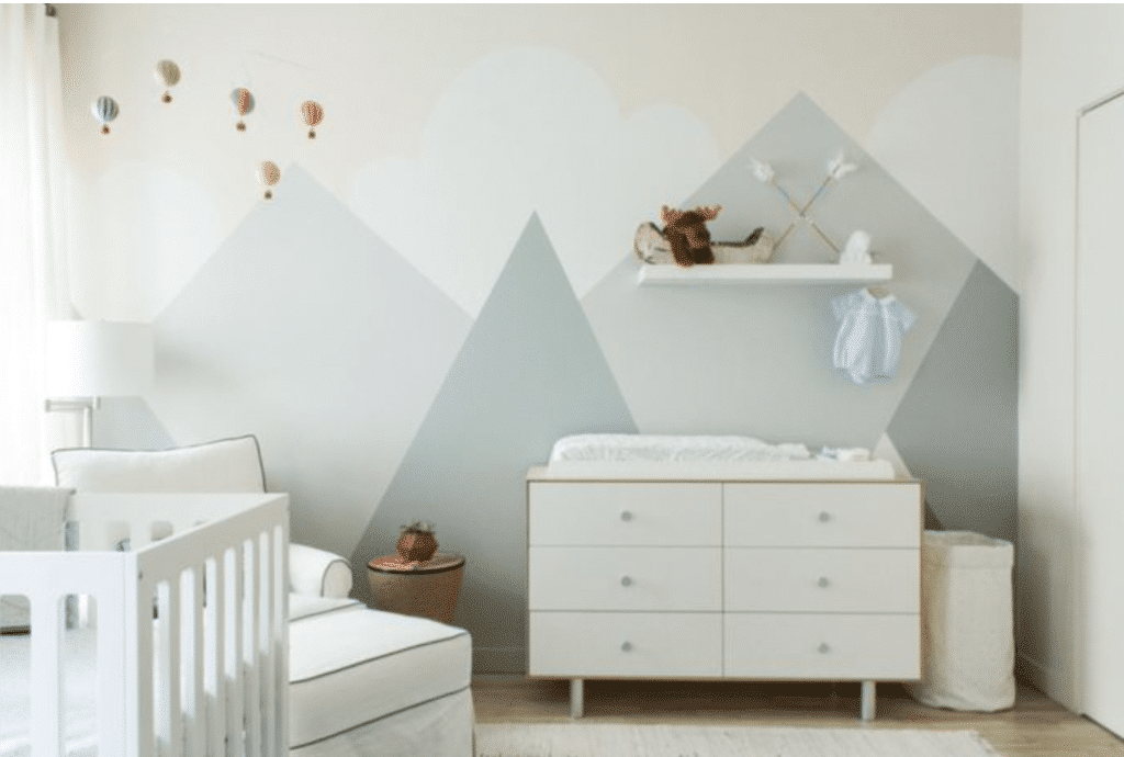 Baby girl nursery with geometric soft grey wall decals, soft white cabinet, white couch and crib inspired by hot air balloons