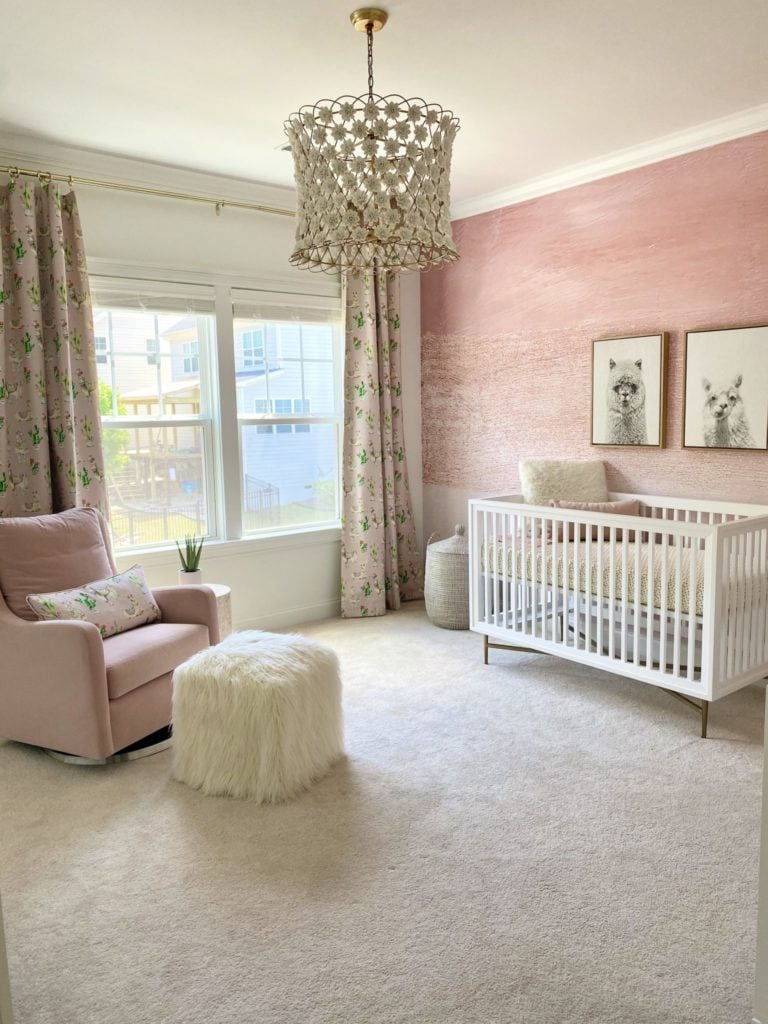 Baby girl nursery with pink and cream walls, pink couch, an accent ceiling lamp and llama wall decor to highlight llama inspired design.