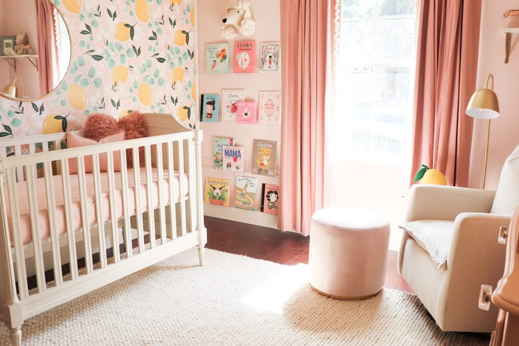 Baby girl nursery with lemon wallpaper, pink curtains and curated books on a bookshelf inspired the pink lemonade design.