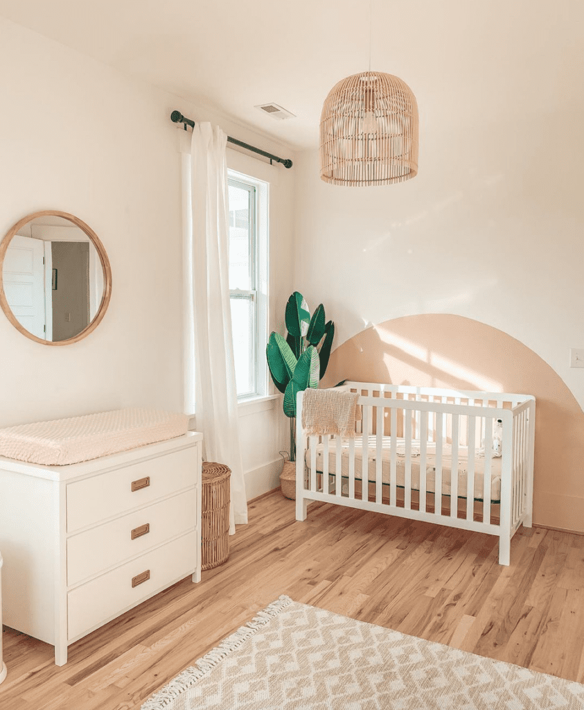 Baby girl nursery with sand toned walls, light wood flooring and white crib and drawers inspired by the soft glow of sunrise.