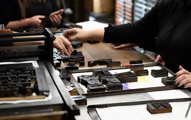 Close-up of a hand rolling ink onto antique wooden type during a letterpress workshop at Bay View Printing Co.