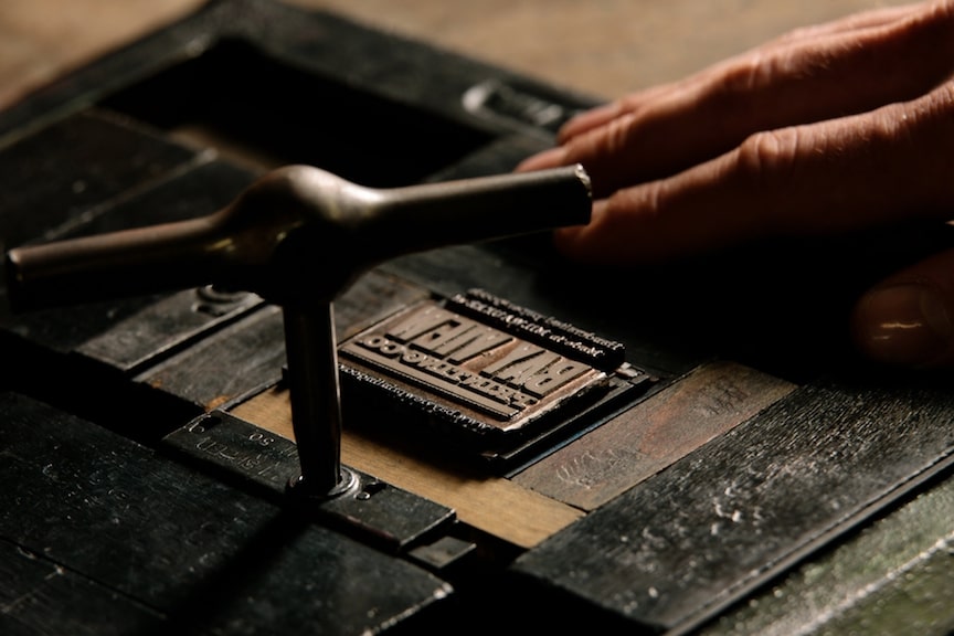 Close-up of a letterpress plate being tightened into place on an antique press at Bay View Printing Co.
