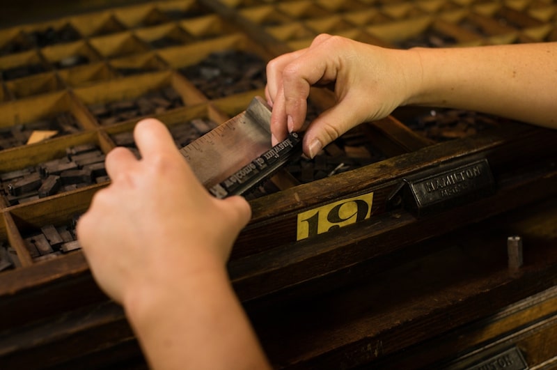 Hands selecting wooden type pieces from an antique Hamilton type drawer during a workshop at Bay View Printing Co.
