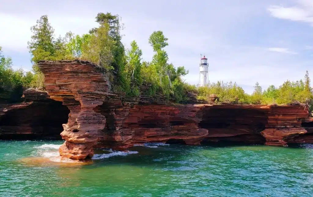 Red sandstone sea caves and lighthouse rising above Lake Superior at the Apostle Islands.