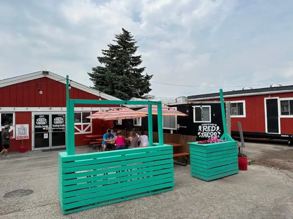 Outdoor seating area at Chucho’s Red Tacos with colorful umbrellas and red buildings.
