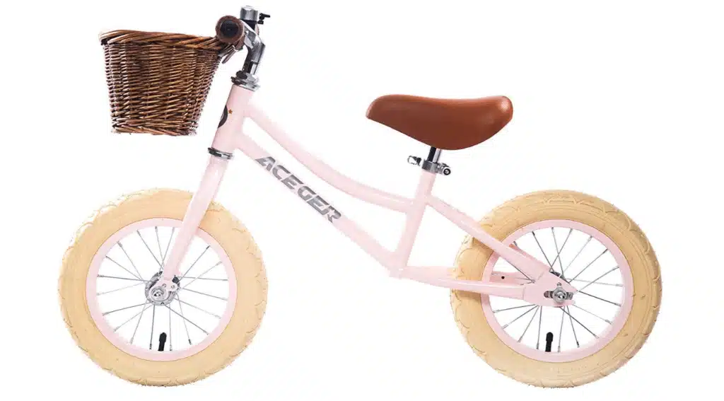 A balance bike with pink body and a woven basket 